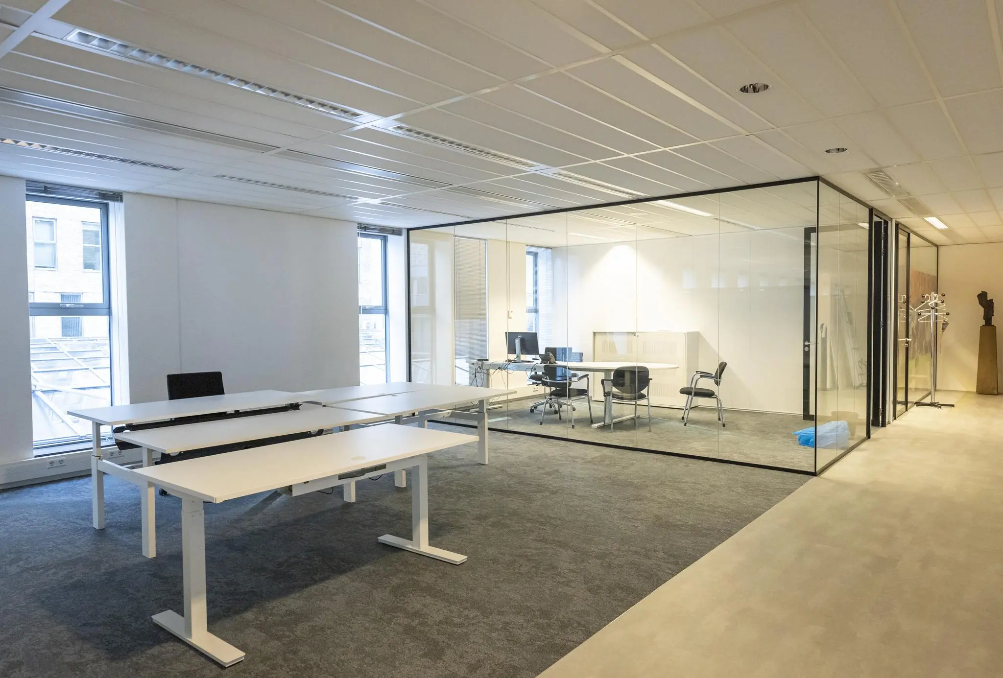 Moderne kantoorruimte aan de Prinses Beatrixlaan met glazen vergaderruimte en verstelbare bureaus.